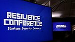 Napis "Resilience conference" na dużym niebieskim panelu.